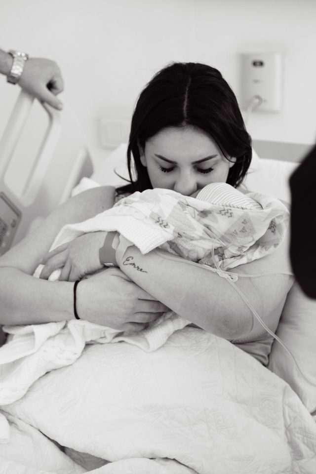 A mother holding her newborn in a hospital bed